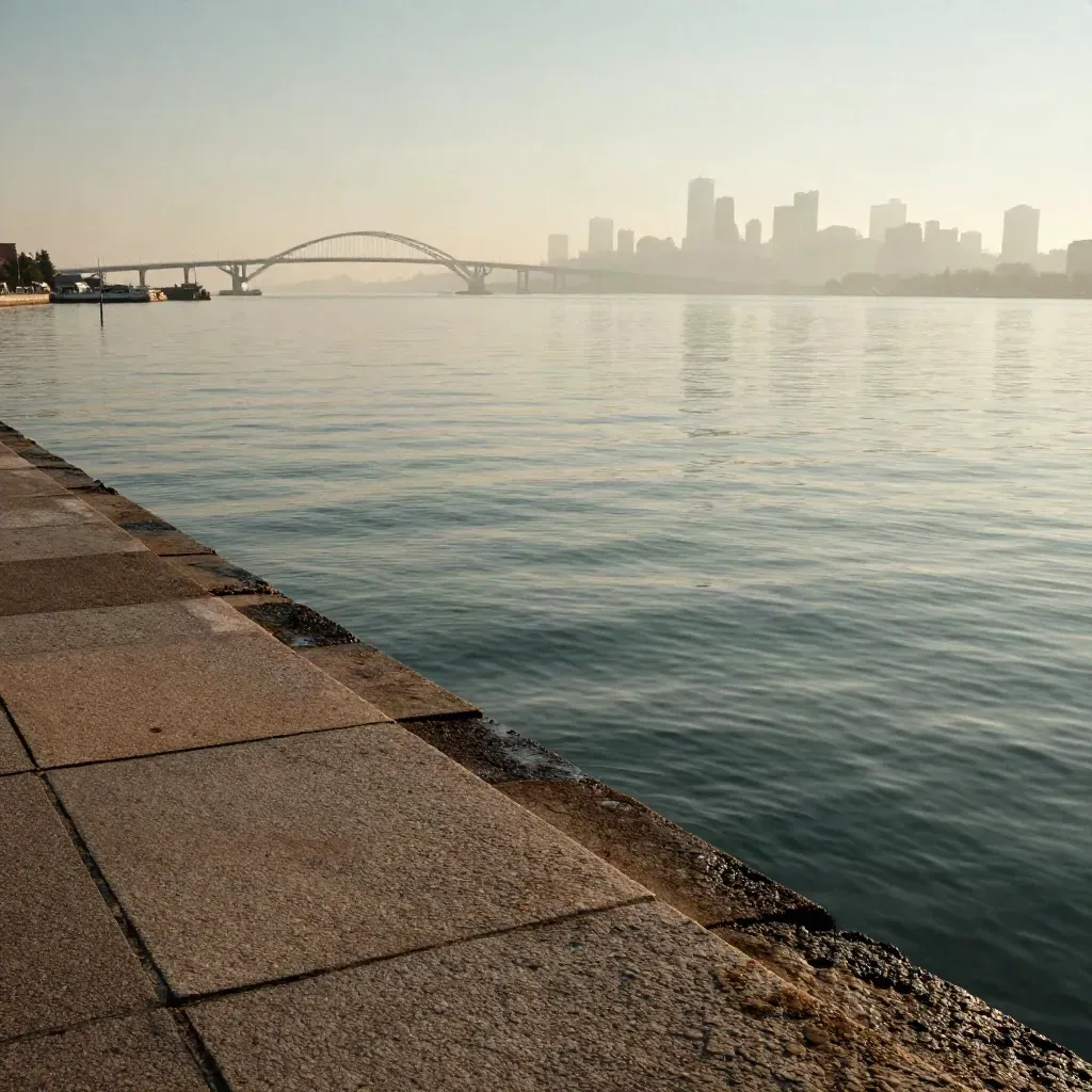 Mist-softened East Coast harbor skyline and bridge above a granite waterfront at sunrise